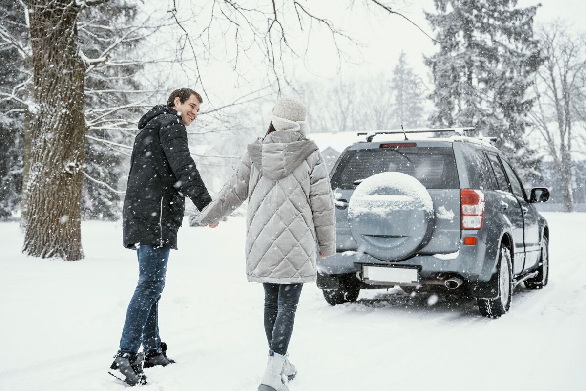 汽车笑脸夫妇在公路旅行中享受雪景的后视图车辆探索冒险