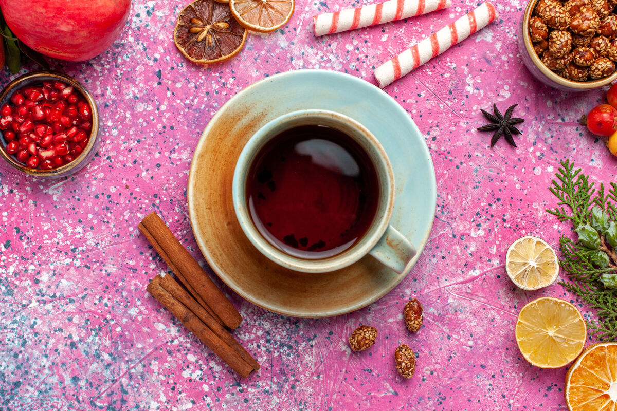 马克杯顶上近距离观赏鲜石榴配上绿叶和一杯红墙上的红茶果实清新醇厚的秋树花色水果新鲜的颜色