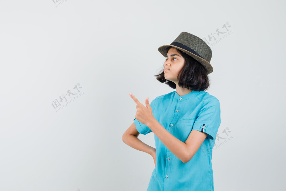而穿着蓝色衬衫 戴着蓝色帽子的年轻女士一边指着一边看可爱指向兴奋