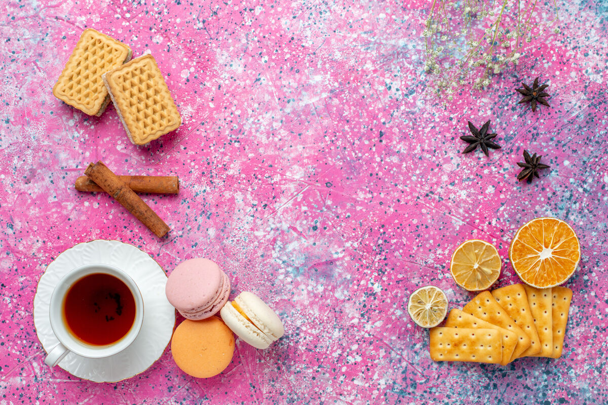蛋糕在浅粉色的桌子上 可以俯瞰一杯茶 里面放着法国马卡龙和饼干法国鲜花茶