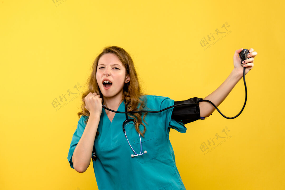 成人正面图年轻女医生在黄色空间测量压力女士医疗器械人