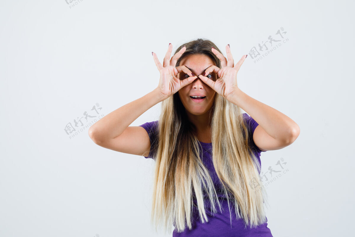 时尚金发女士展示眼镜的姿势在紫罗兰色t恤衫 看起来很惊讶 前视图魅力漂亮手势