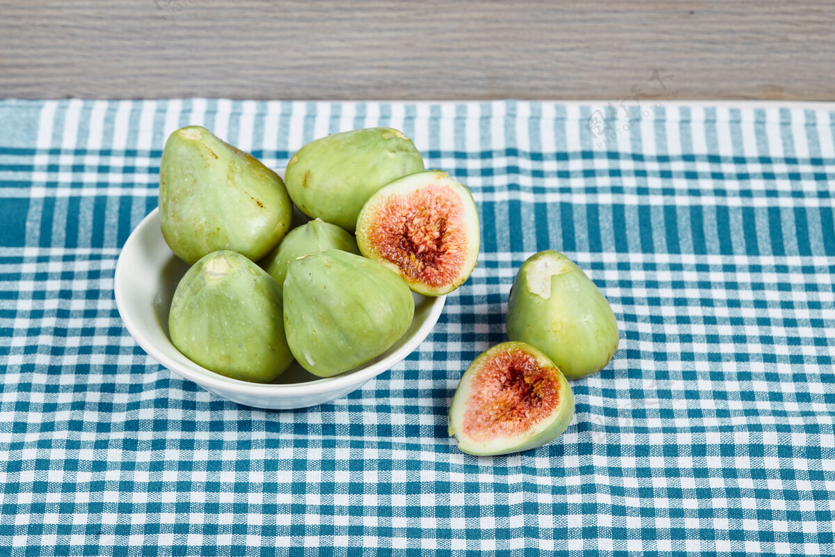 食物绿色的无花果放在一个白色的碗里 放在一张铺着蓝色桌布的木桌上热带健康桌布