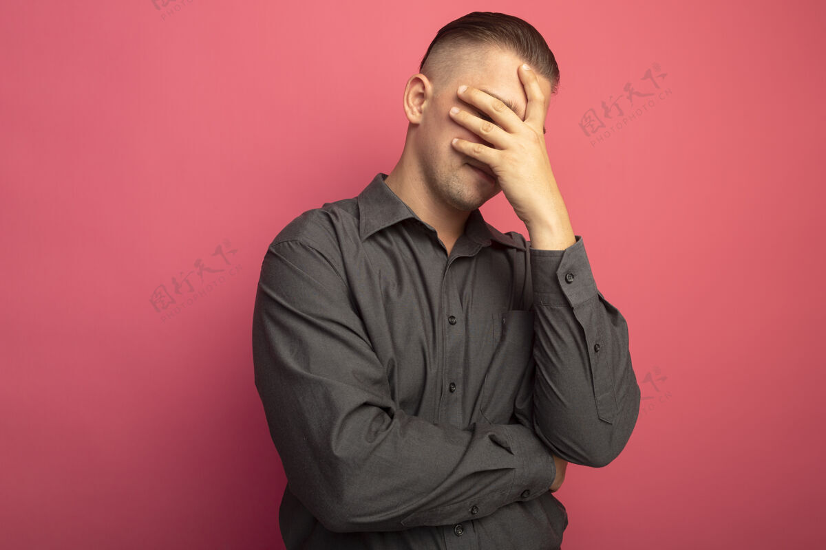 面部表情一个穿着灰色衬衫 手捂着脸的年轻帅哥 站在粉色的墙上 又累又无聊脸男人人