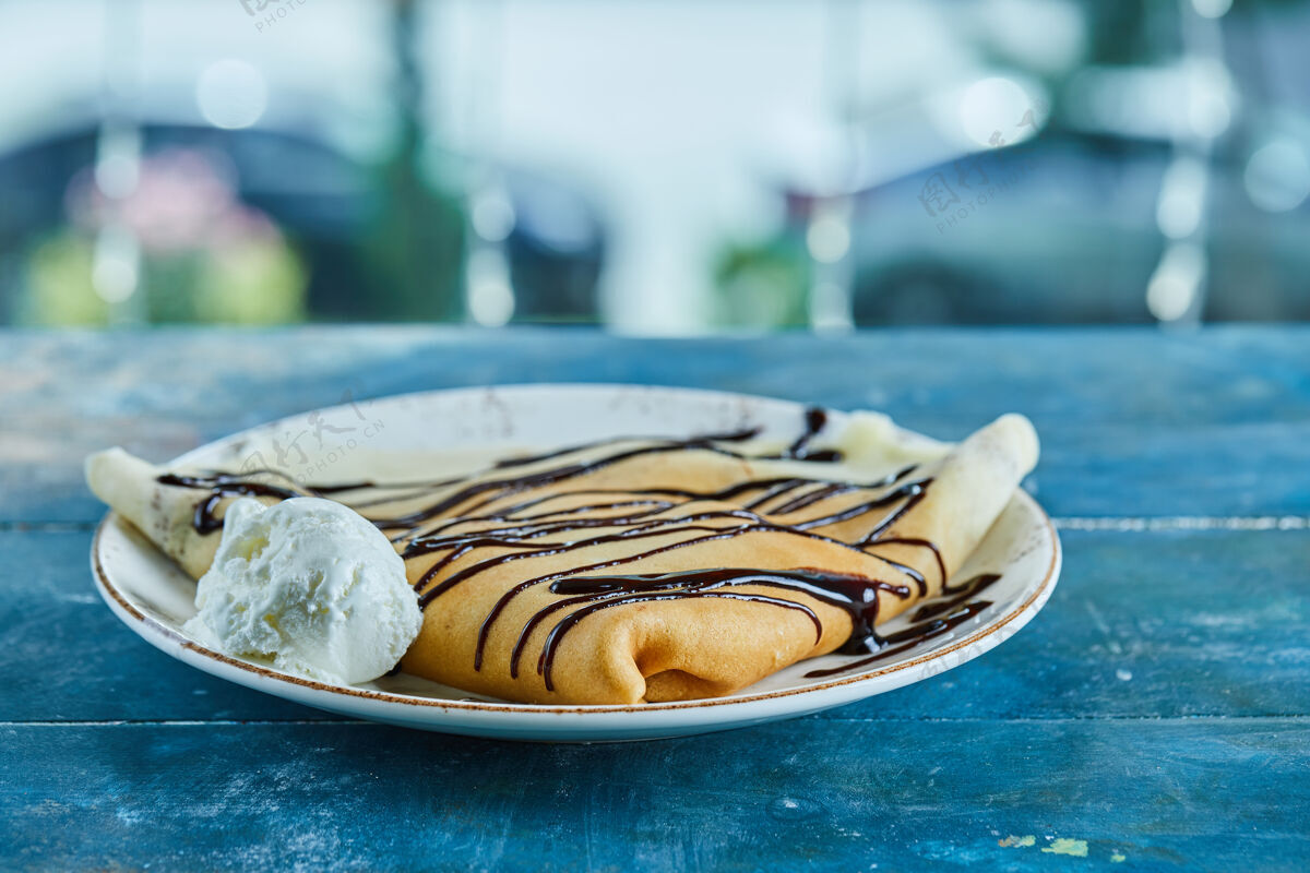 鞭子薄煎饼配香草冰淇淋 巧克力放在蓝色的白色盘子里薄煎饼吃的食物