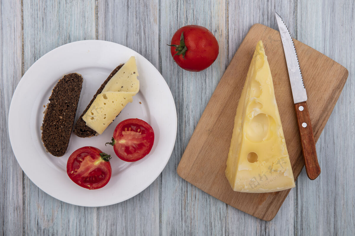 顶部俯瞰玛斯丹奶酪 刀架上放着西红柿和黑面包片 盘子的背景是灰色的切片视图奶酪