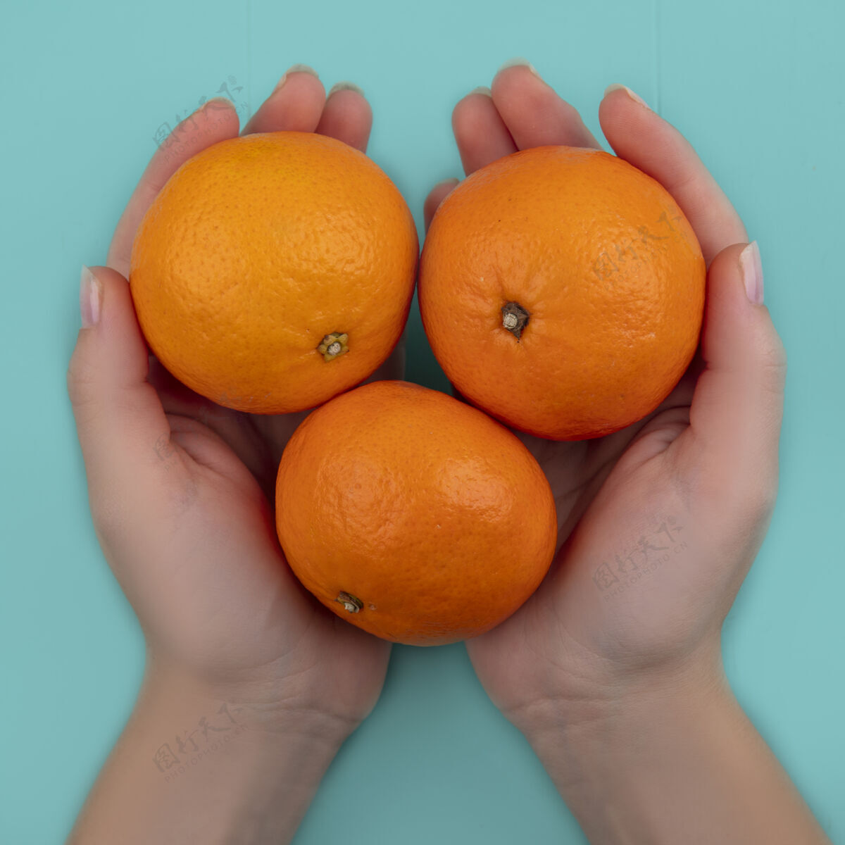水果俯视图：手拿橘子的绿松石背景的女人绿松石色顶部橙色