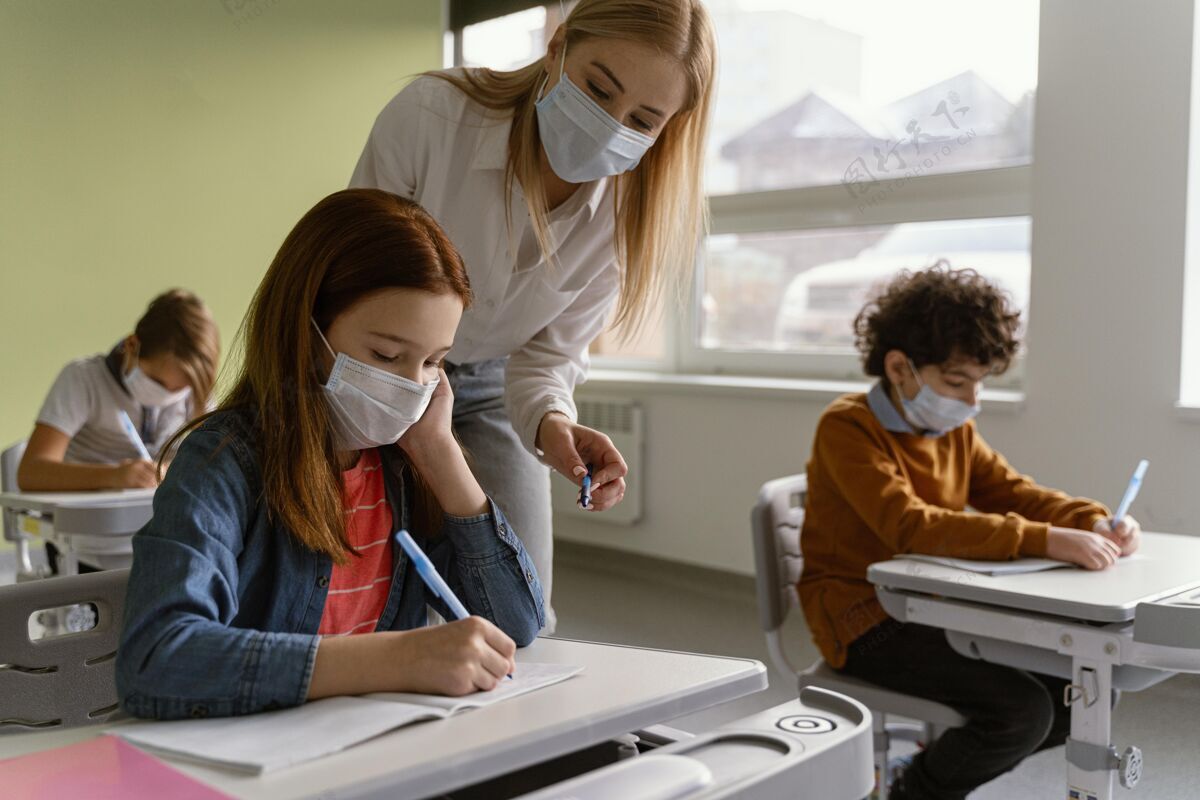 学习戴着医用口罩的孩子在学校和老师一起学习冠状病毒学习教师