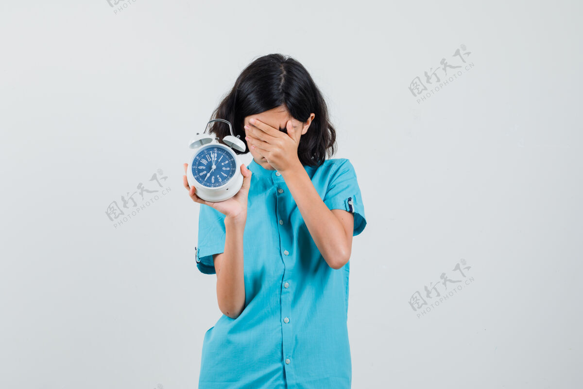 持有穿蓝色衬衫的女学生一边用手捂着脸 一边展示时钟 看上去很担心蓝色看可爱