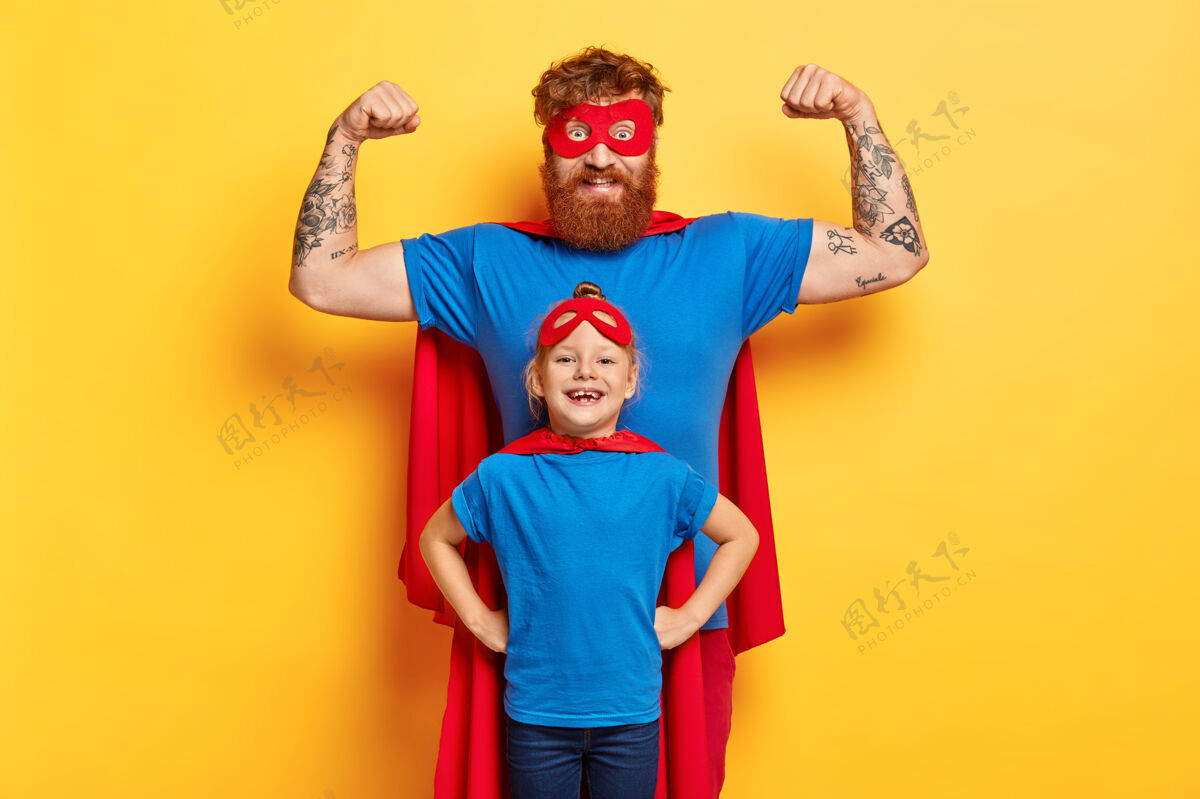 狡猾家庭乐趣的概念快乐坚强的父亲举起双臂 展示肱二头肌 准备保卫他的女儿红发防守强壮