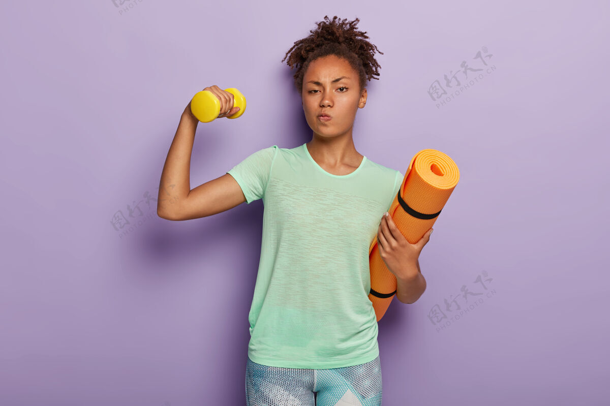 紧身裤漂亮的运动女人训练肱二头肌 举起哑铃身材运动装严肃