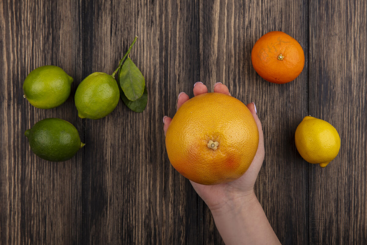 水果顶视图女人拿着柚子和柠檬橙和柠檬在木制背景上柠檬新鲜酸橙