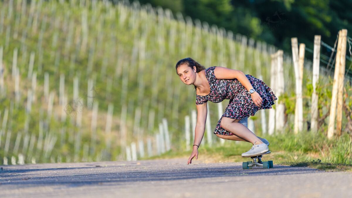 绿色年轻女子在绿树环绕的空旷路上滑滑板活动运动自然