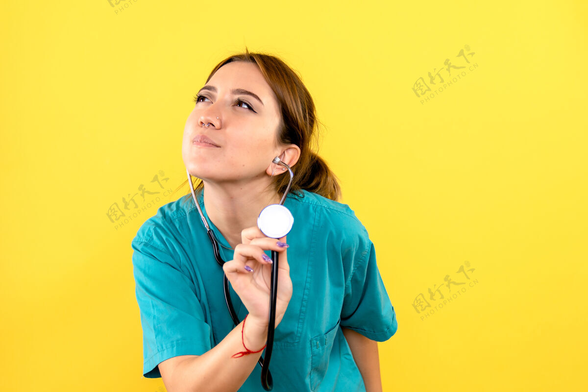 人黄色墙上带听诊器的女兽医的正视图宠物医院微笑