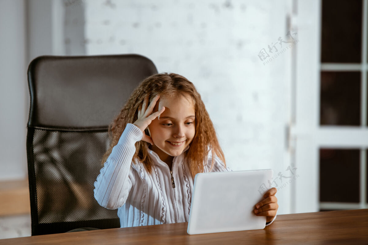 人类年轻的白人女孩的肖像看起来梦幻 可爱和快乐抬头看 坐在室内的木桌与平板电脑和智能手机未来的概念 目标 梦想购买 可视化奇迹孩子健康