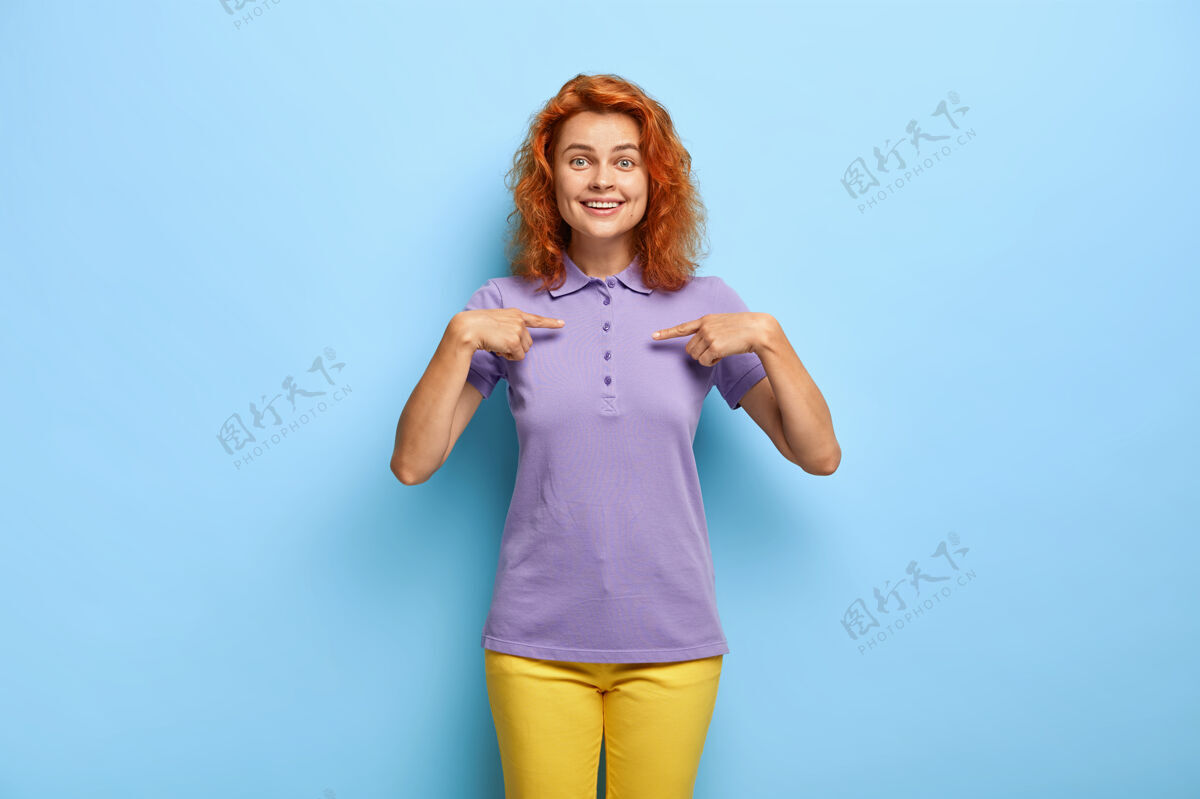 女性化喜气洋洋的红发女人指着t恤的空白处发型服装满意