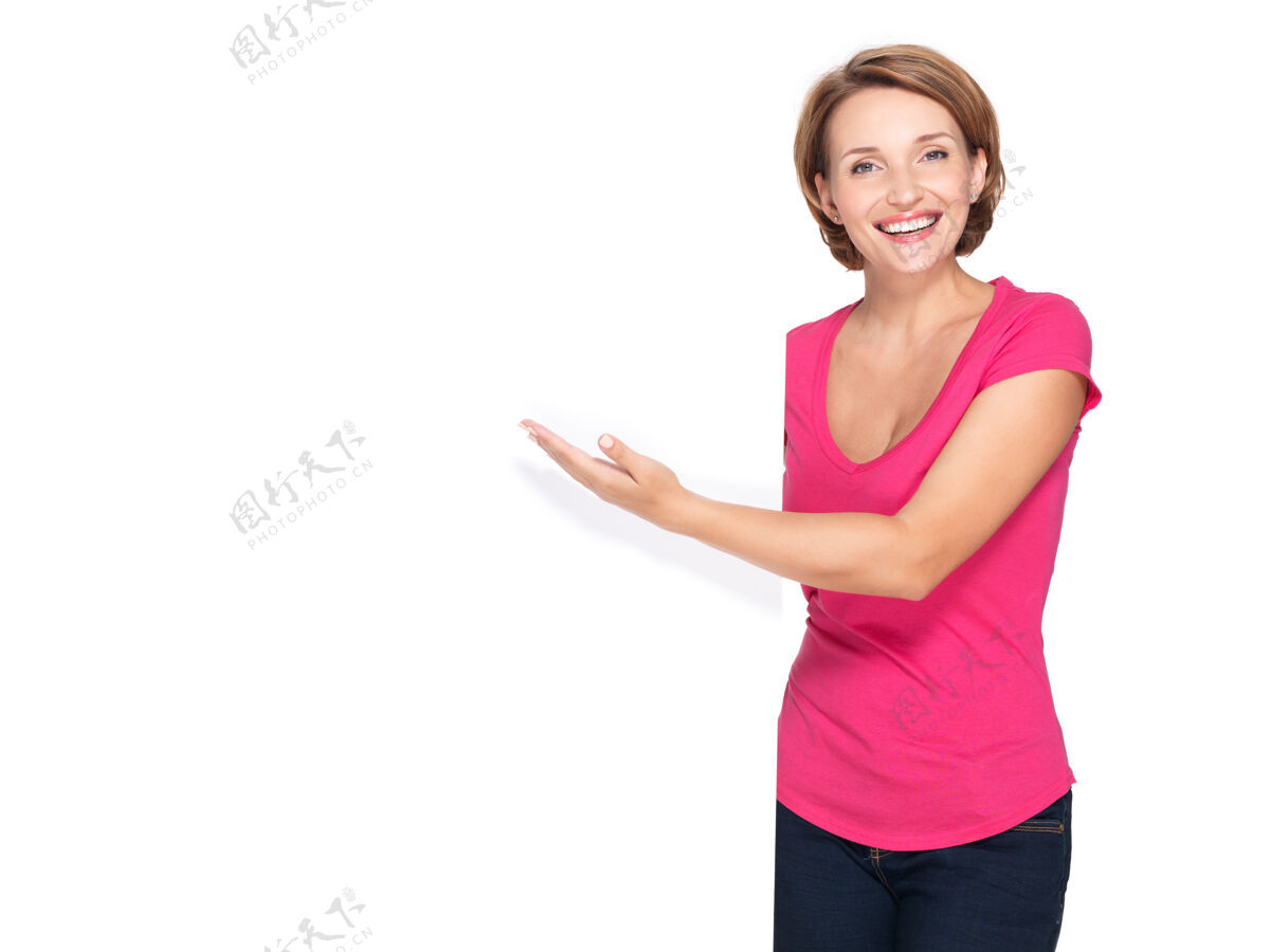 广告快乐的女人用手指着隔离在白墙上的横幅指向年轻广告