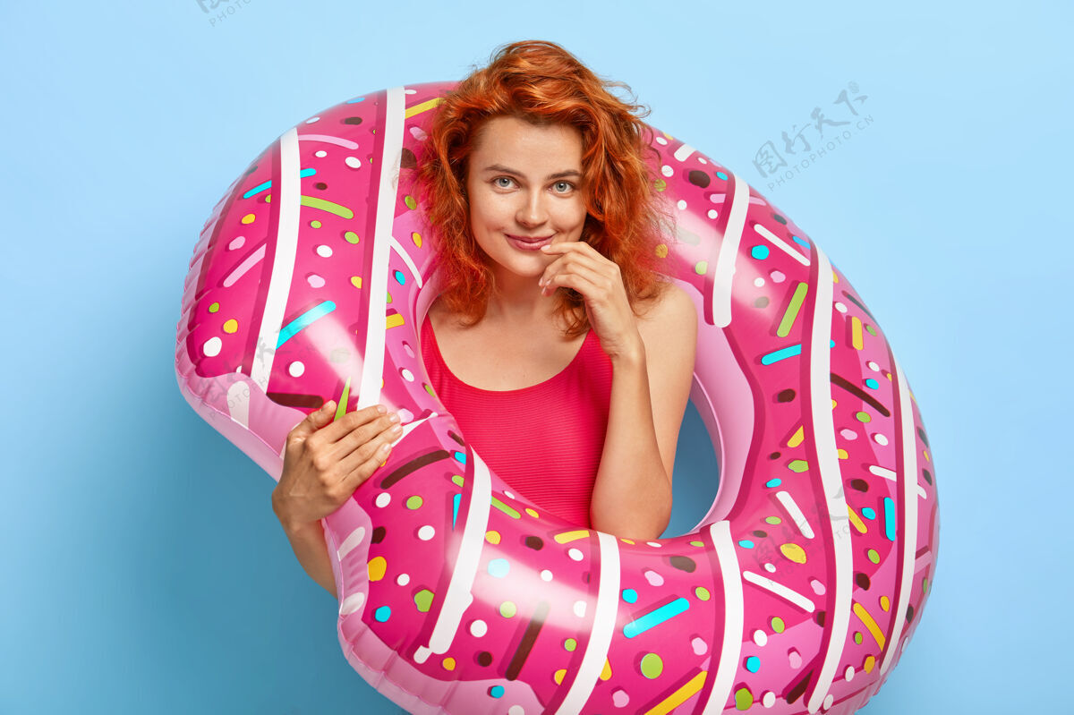 游泳池照片中可爱的姜女神采奕奕 在橡胶游泳圈内摆姿势 身着泳装 在海边休息休息欢笑热带