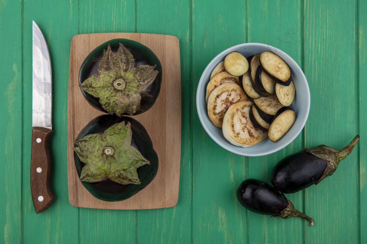 蔬菜顶视图黑色茄子与一个绿色背景上的砧板刀切板西葫芦
