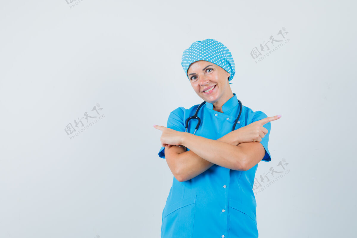 妇女穿着蓝色制服的女医生指着别处 看上去很高兴 正对着前方工作人员疾病年轻人