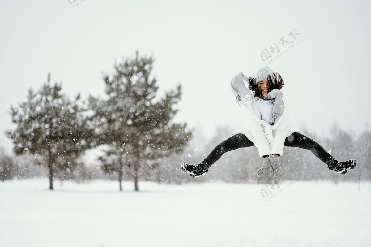 雪妇女在户外空中跳跃的正面视图女人姿势人类