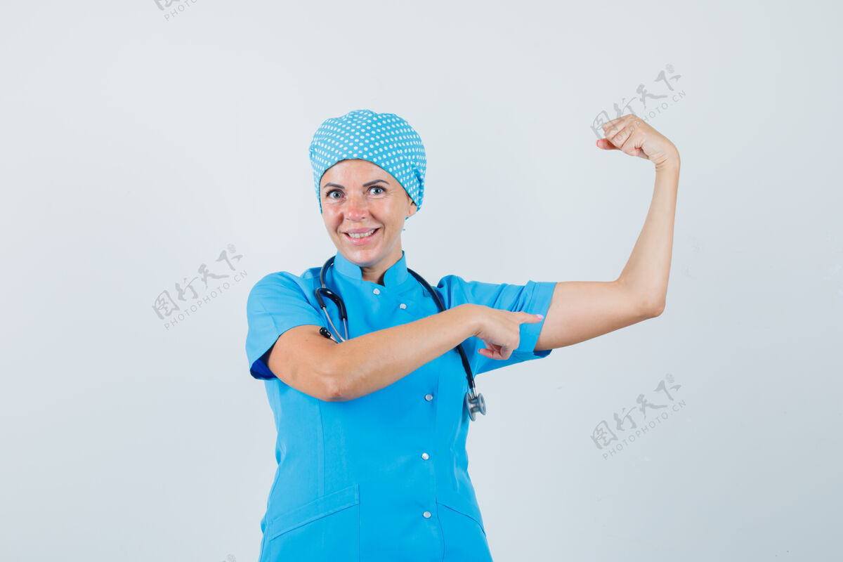 病人女医生指着身着蓝色制服的手臂肌肉 看上去很自信前视图职员诊断外科医生
