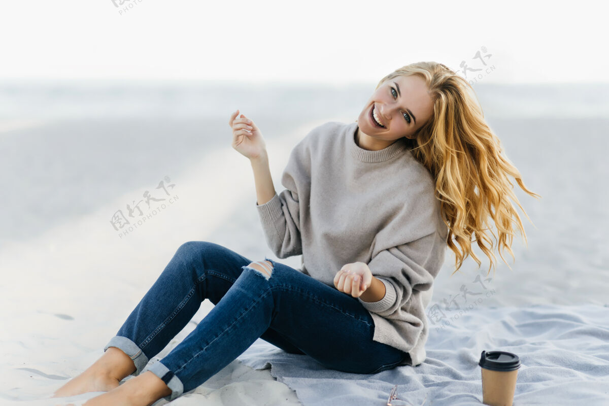 大海热情的白种女人在沙滩上表达秋日的快乐穿着牛仔裤的年轻女人在大自然中微笑周末无忧无虑沙滩