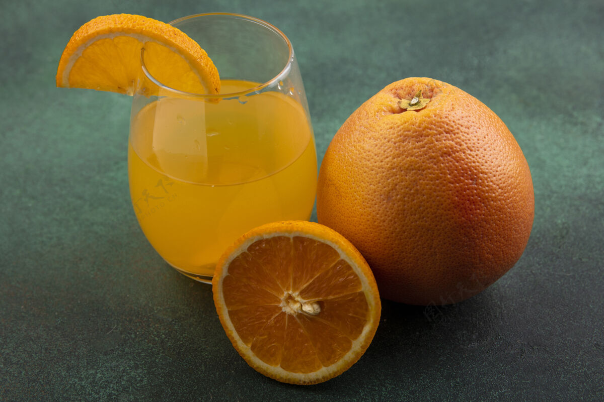 饮料前视图橙汁在玻璃上与橙色和葡萄柚绿色背景果汁橙色玻璃