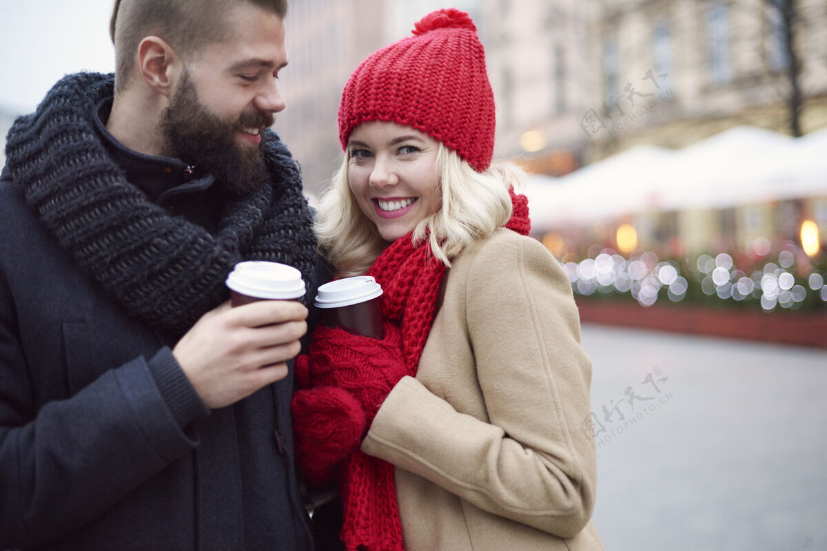 男人情侣在户外喝热咖啡热身冬天牙齿微笑