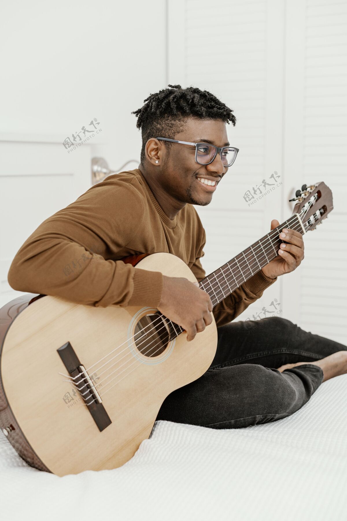 表演侧视图笑脸男音乐家在家里弹吉他在床上乐器创意房子