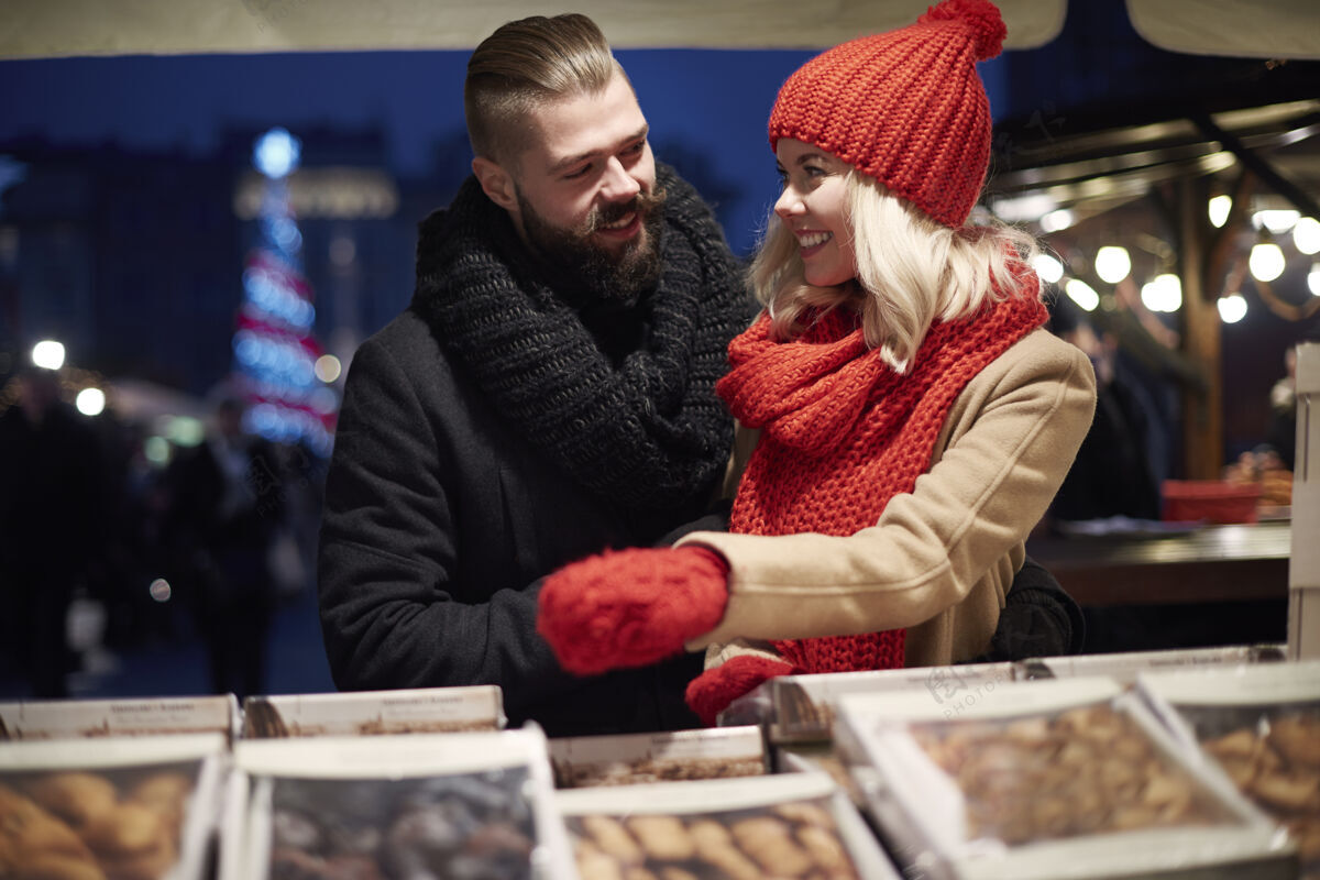 甜情侣在当地市场买糖果冷假日帽子