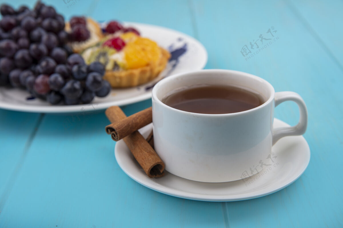 蓝色一杯茶的侧视图与肉桂棒在蓝色的木制背景上杯子壁板杯子