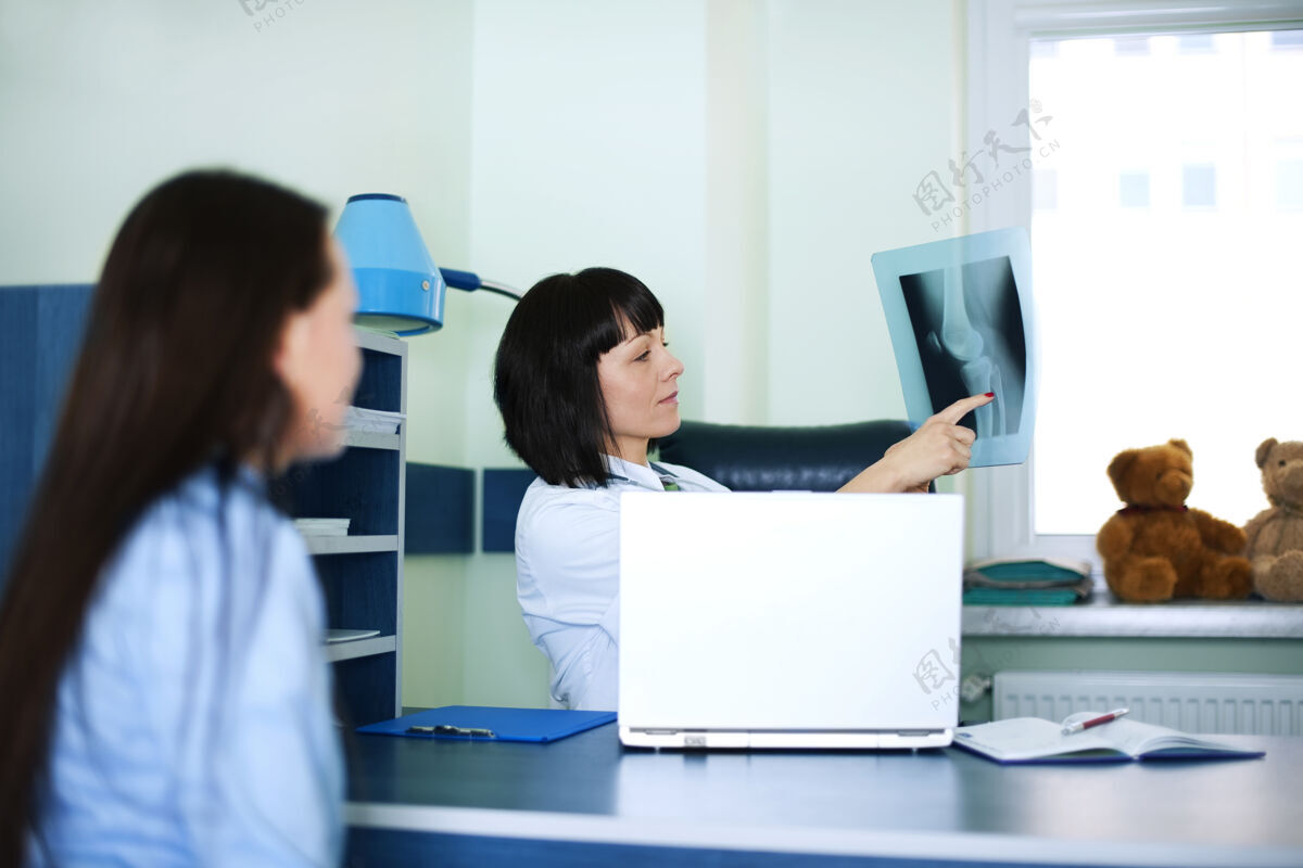 疾病年轻的女人和医生在看x光片台灯工作看