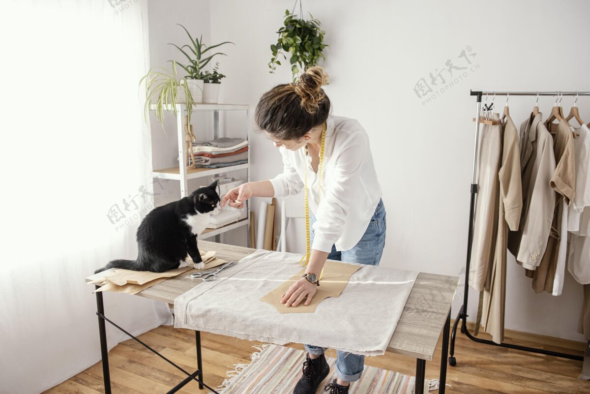 缝纫女裁缝和猫在工作室工作缝纫昂贵的水平