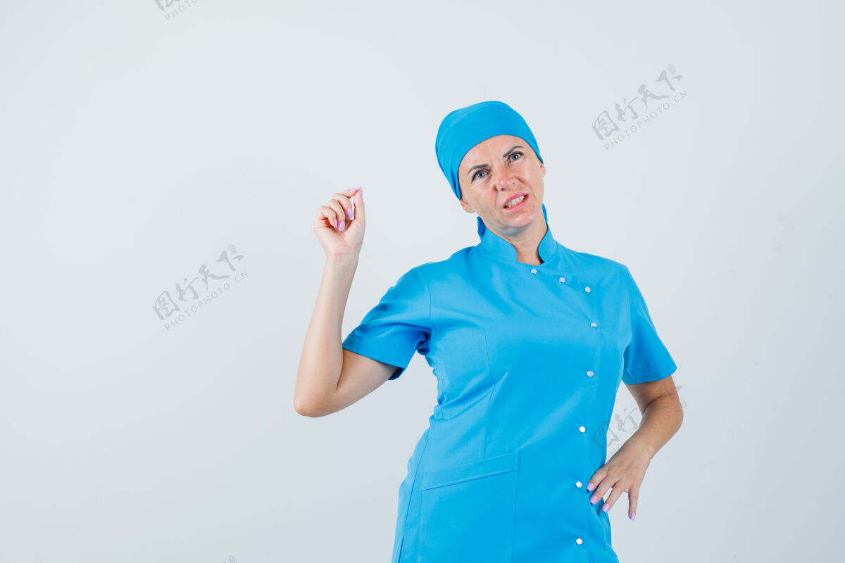 制服穿着蓝色制服的女医生正在量着一件很小的东西 面带沉思的样子 前视图护士职员诊所