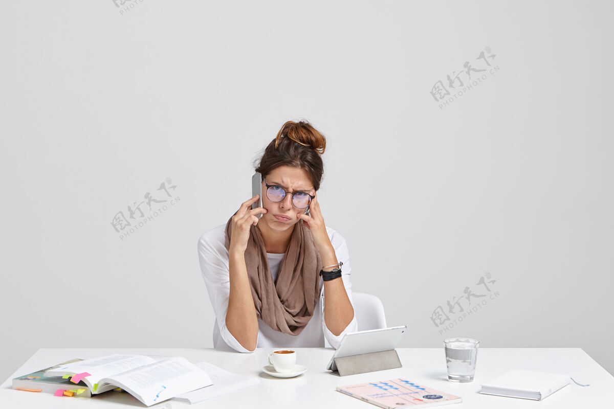 坐着紧张的女企业家在数字平板电脑工作期间通过手机交流压力恐慌镜头