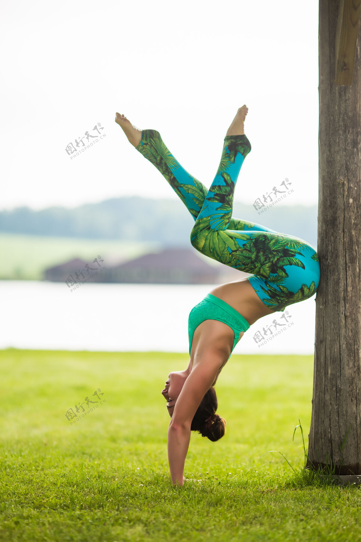 瑜伽可爱的年轻女子在绿色公园做倒立练习训练可爱活动