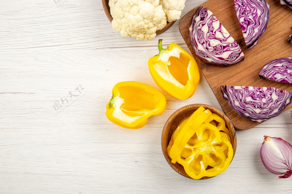 碗顶视图切碎的红卷心菜放在木板上切碎的洋葱切碎的黄甜椒花椰菜放在碗里放在白色的桌子上自由空间花板观点