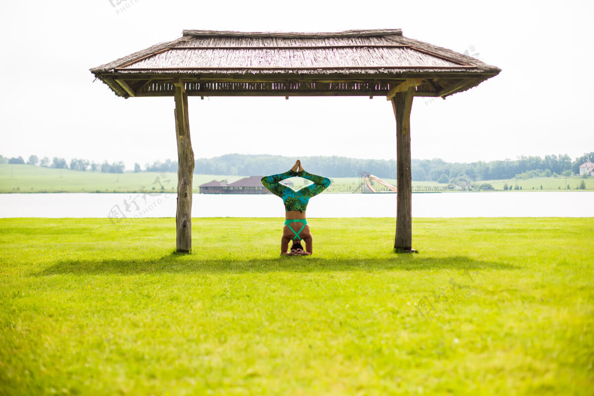 力量夏日公园里赤脚年轻女子做倒立的侧视图体位姿势姿势