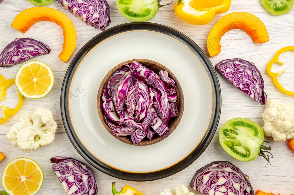 圆俯视图切红白菜在碗里放在圆盘子上切蔬菜在白桌子上蔬菜面食切红白菜