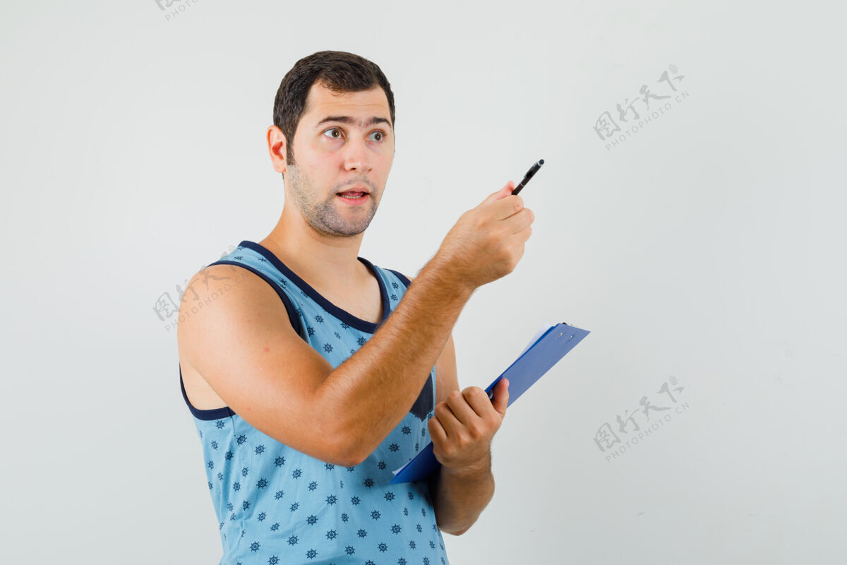 脸年轻人指着别处 拿着蓝色单件的剪贴板 看上去很困惑正视图抱着自信肖像