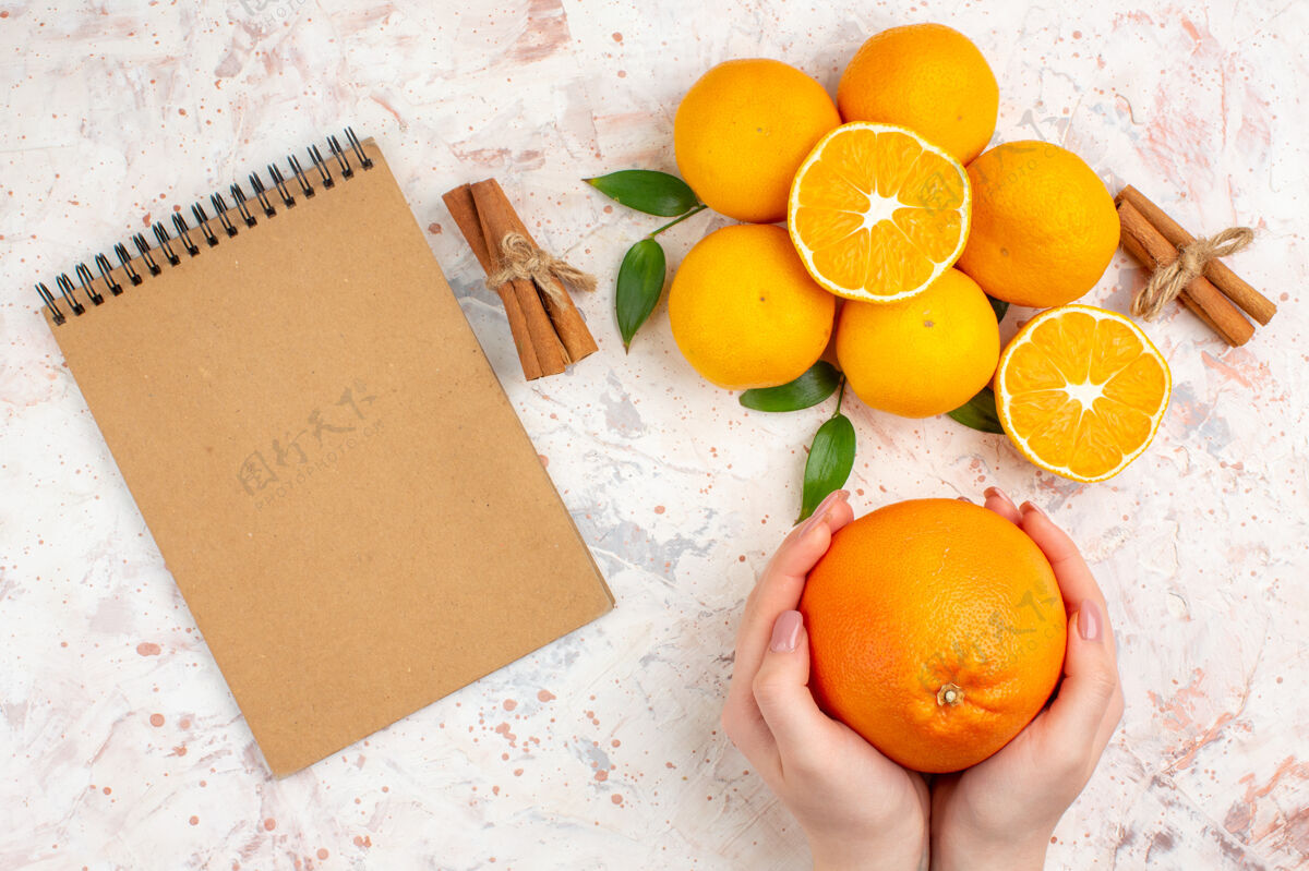 切割顶视图新鲜的柑桔肉桂棒切橘子在女人手里一个笔记本上明亮的孤立的表面维生素笔记本顶部