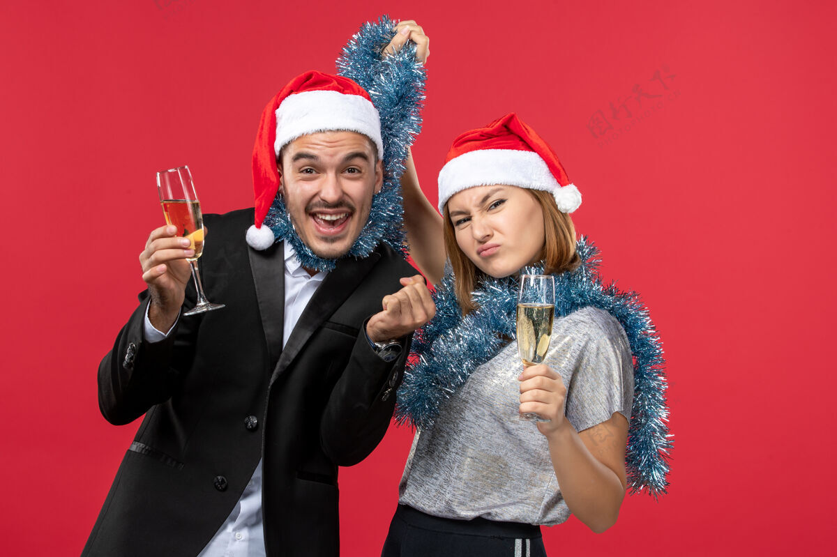 年轻夫妇正面图年轻夫妇在红墙庆祝新年爱圣诞节圣诞帽子风景
