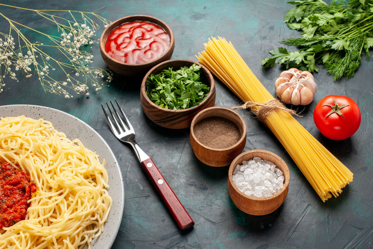 配料半俯视图煮熟的意大利面食 蓝色表面有肉和不同的调味品午餐调味品肉