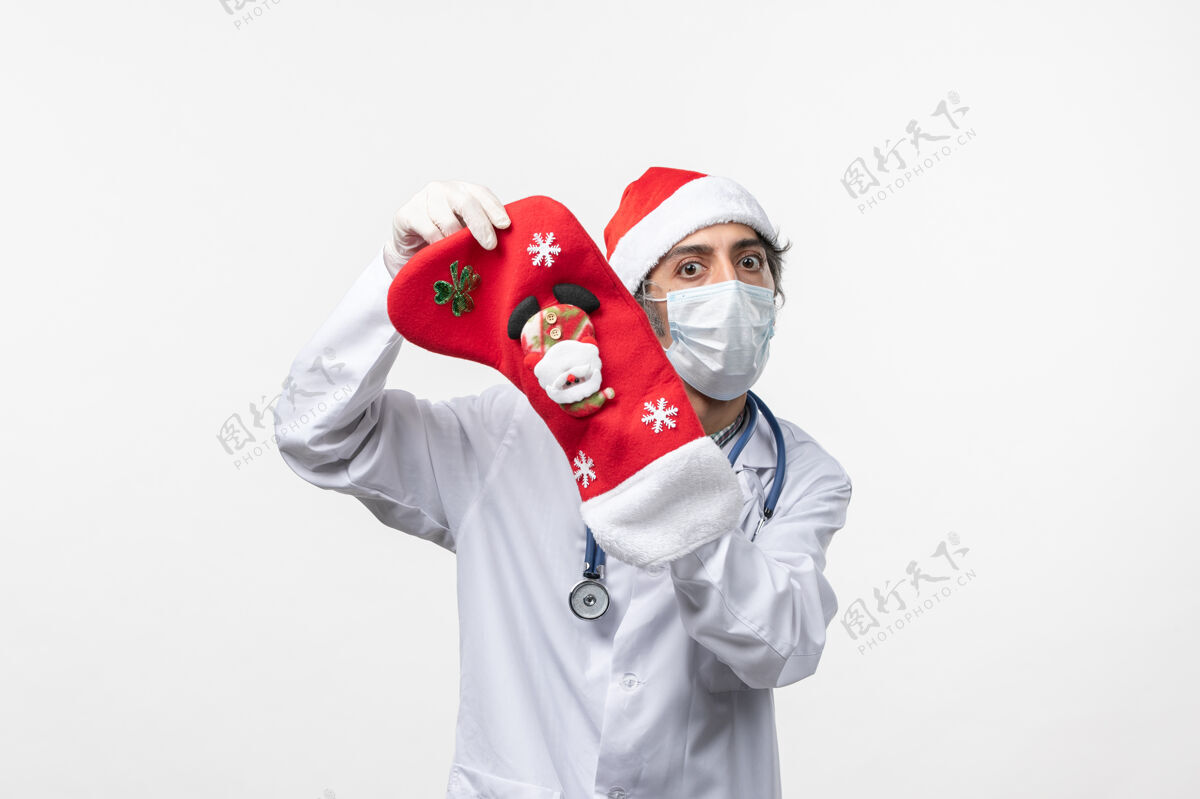服装正面图白色办公桌上戴着大节日袜子的男医生-圣诞病毒喜剧演员男人表演