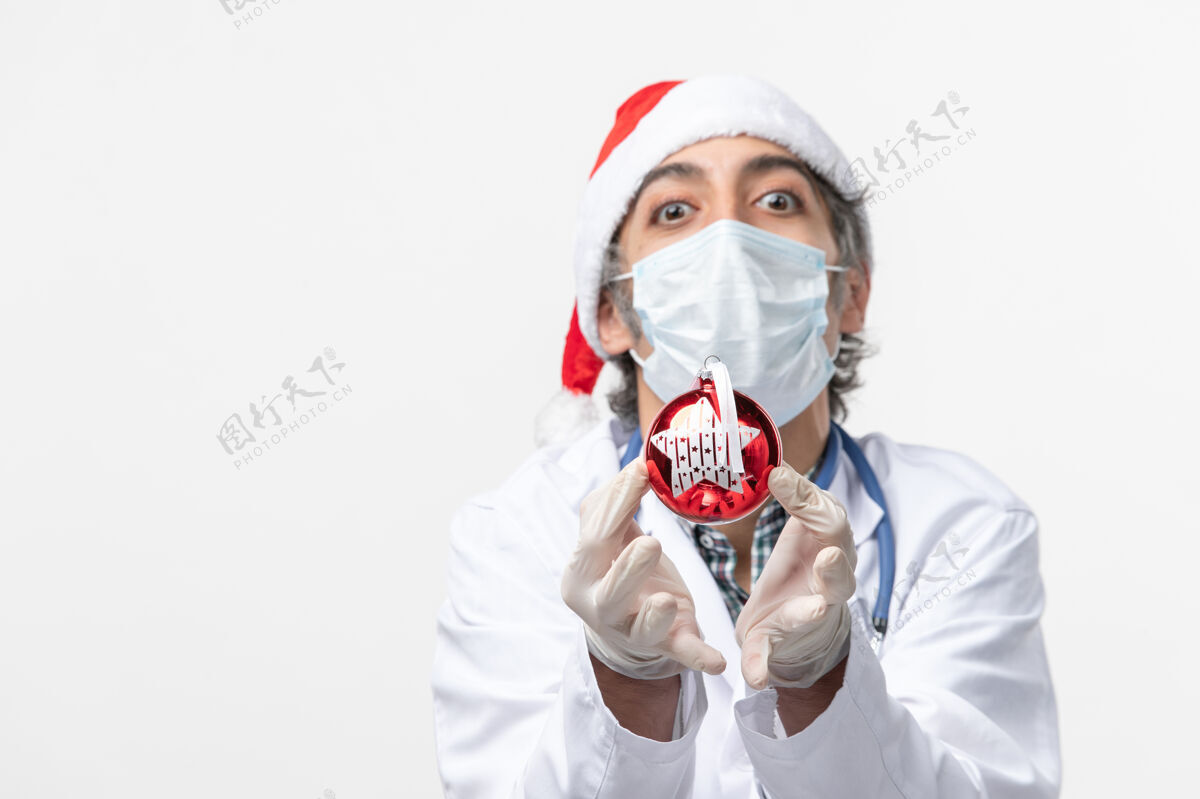 冠状病毒正面图男医生戴着口罩和玩具在白色地板上健康共舞新年病毒外套药品制服