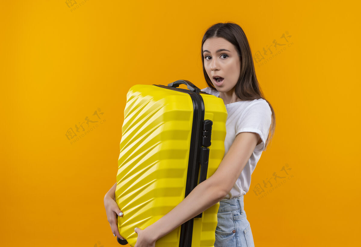 年轻年轻漂亮的旅行女孩拿着手提箱 看上去既惊讶又惊奇惊喜旅行者抱着