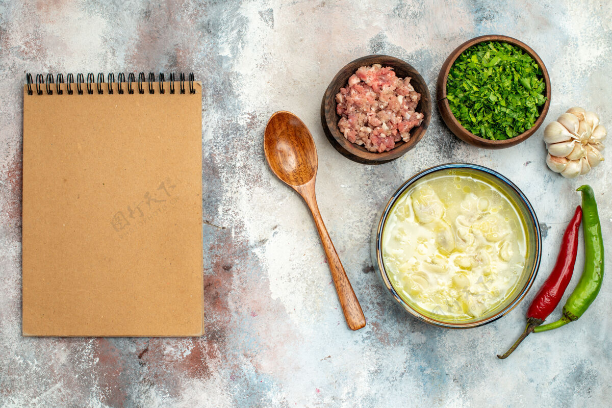 绿色俯瞰杜什巴拉饺子汤碗大蒜辣椒木勺碗肉和绿色笔记本裸体表面碗晚餐勺子