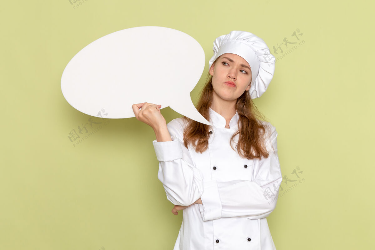 浅绿色身穿白色厨师服的女厨师手持白色标牌 在浅绿色墙上思考女性肖像漂亮
