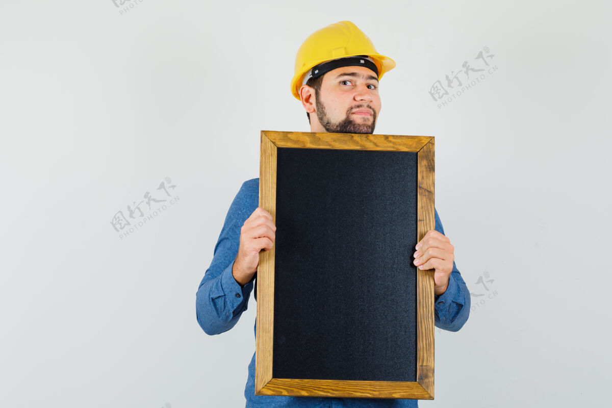 成人年轻男子手持黑板 身穿衬衫 头戴安全帽 神情乐观 俯视前方专业胡须模特